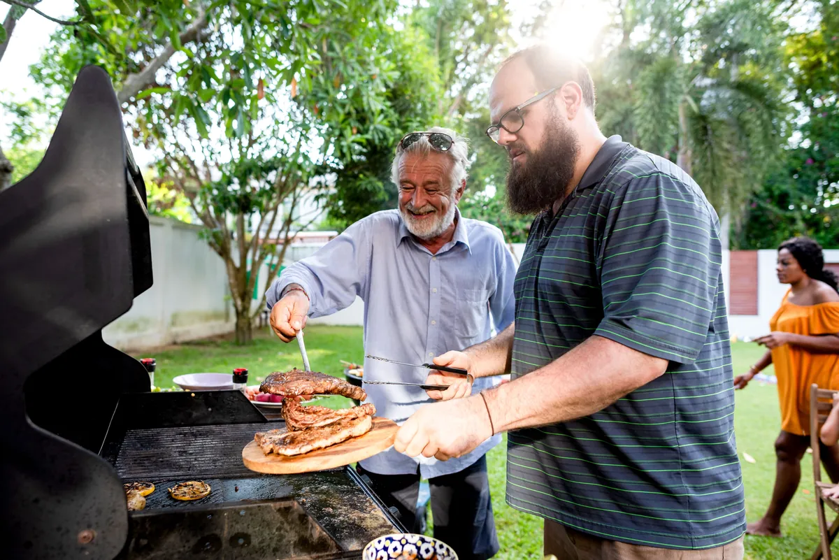 Friends cooking at a backyard barbecue on a sunny day