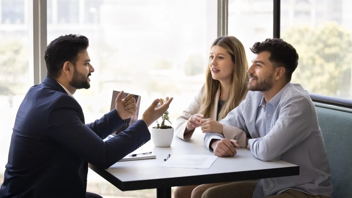 Young Indian couple meeting an adviser at a table in a bright office