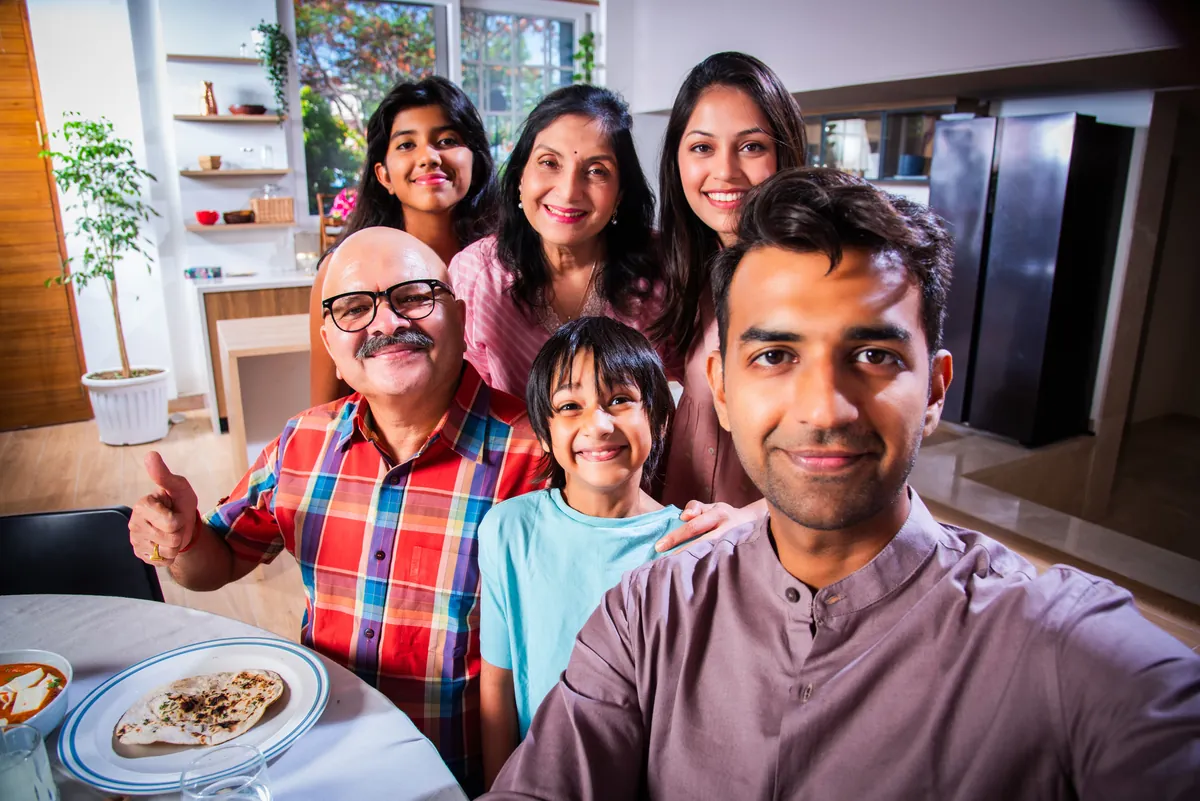Indian grandparents, parents and grandchildren smiling together at home