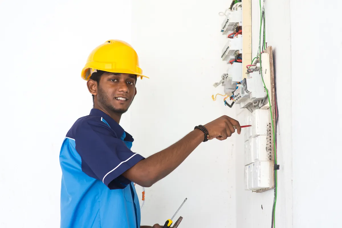 Young electrician in a hard hat working on a switchboard