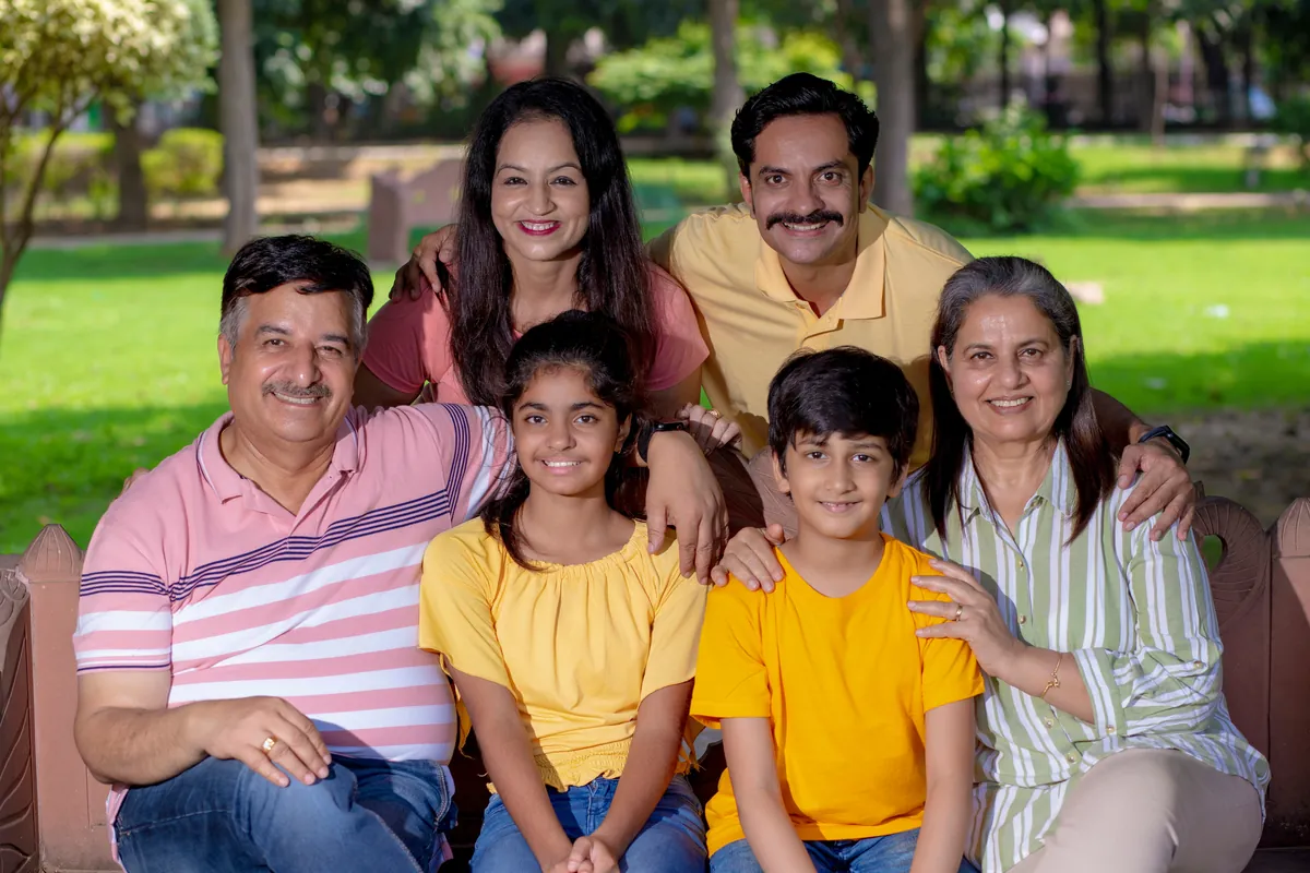 Three-generation Indian family smiling together in a green park