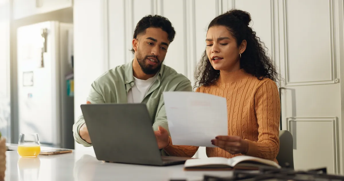 Couple reviewing documents together at a laptop at home