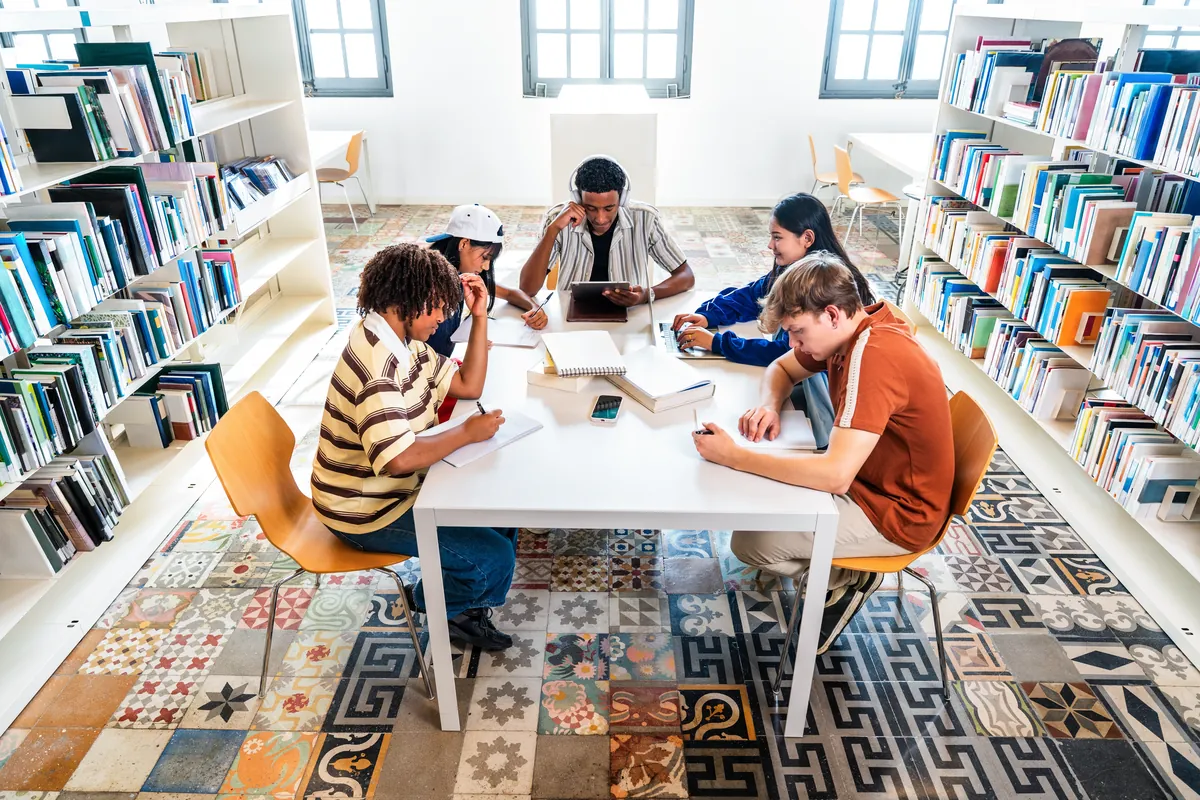 Students studying together at tables in a bright library