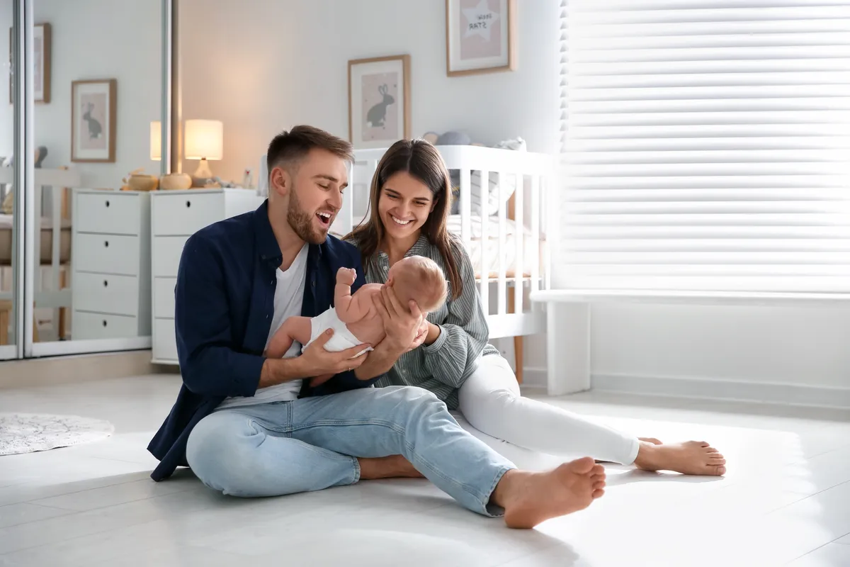 Young parents holding their baby in a bright nursery