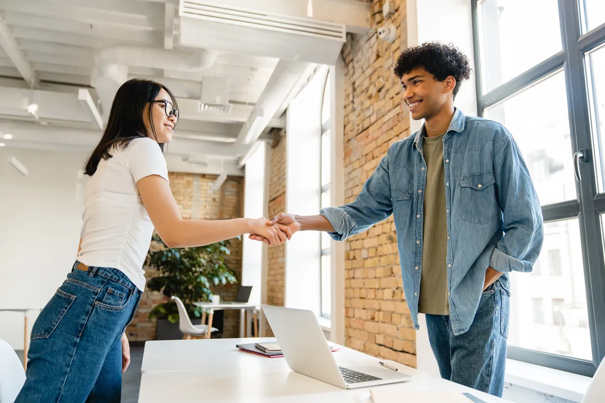 Young worker shaking hands with a colleague in a bright office